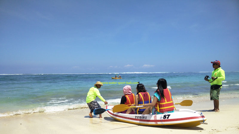 Wisatawan bersiap untuk kano di Secret Beach Bali dengan instruktur yang membantu