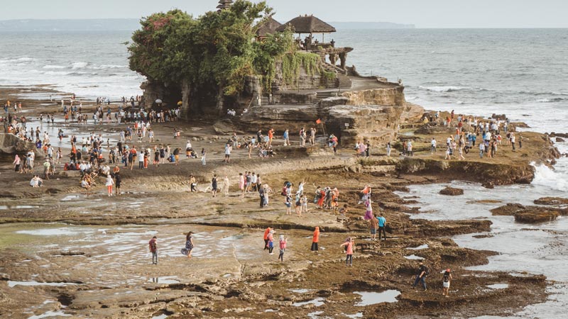 Wisatawan berkunjung ke Pura Tanah Lot Bali pada sore hari. 20 Tempat Wisata Untuk Dikunjungi Bali