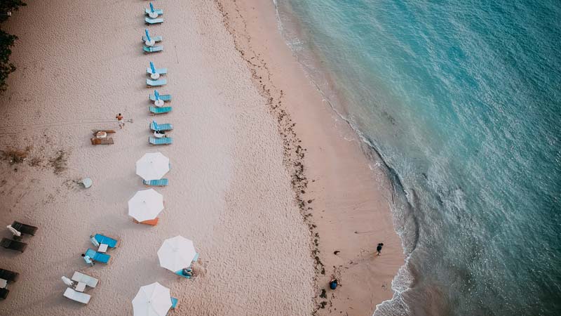 Pemandangan udara Pantai Karang Sanur dengan payung-payung pantai yang tertata di tepi laut biru