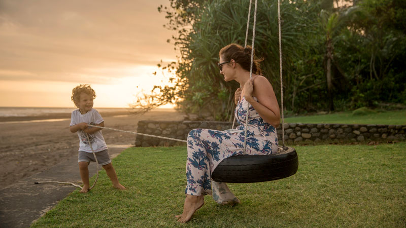 Ibu dan anak menikmati waktu bermain di pantai Bali saat senja