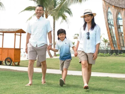 Keluarga bahagia berjalan di taman resort tepi pantai Legian, Bali