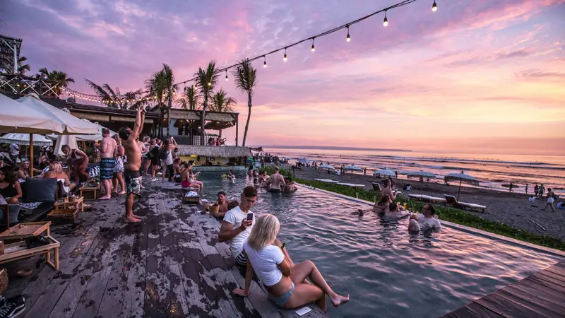 Pengunjung menikmati kolam renang dan matahari terbenam di bar tepi pantai di Canggu