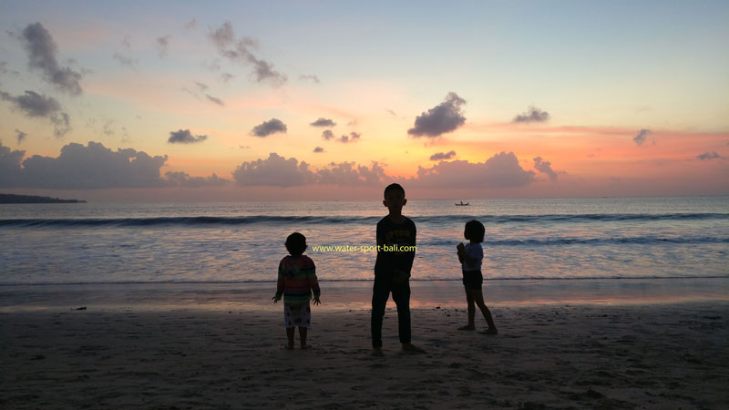 Siluet keluarga menikmati matahari terbenam di Pantai Jimbaran, Bali