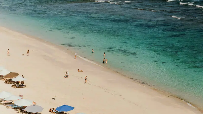 Pantai Thomas Uluwatu dengan pasir putih dan air laut jernih, cocok untuk bersantai dan berselancar ringan