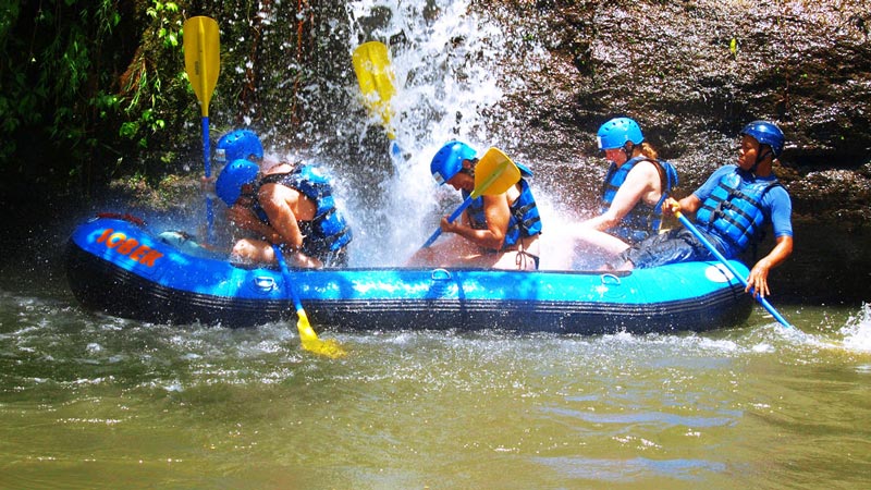 Rafters dengan helm biru dan rompi penyelamat menavigasi jeram kelas 1 di Bali. Panduan Klasifikasi Tingkat Kesulitan Jeram Sungai