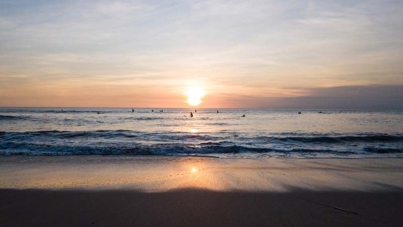 Matahari terbenam di Pantai Kuta dengan siluet peselancar di Bali