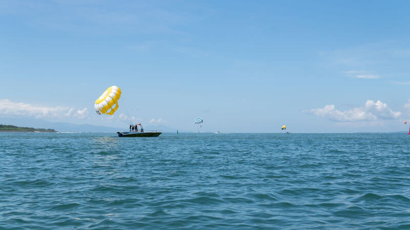 Parasailing adventure di Bali dengan latar belakang pemandangan pantai, bagian dari 5 Hal Yang Perlu Diketahui Tentang Bali Parasailing.