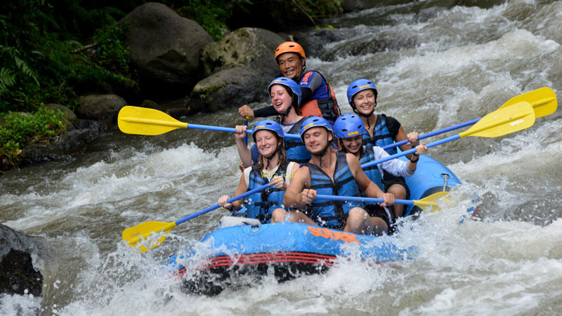 Kelompok wisatawan bersama pemandu rafting menikmati arung jeram di Sungai Telaga Waja