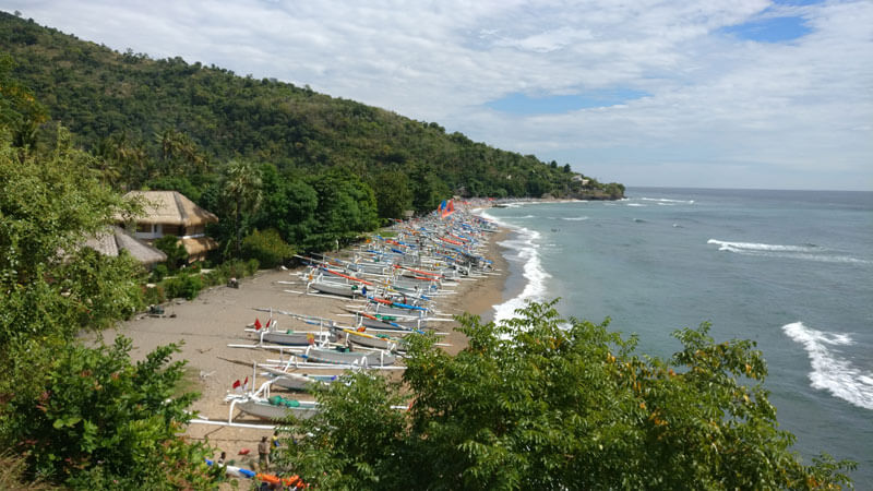 Perahu-perahu nelayan di Pantai Amed dengan latar belakang bukit hijau dan laut biru