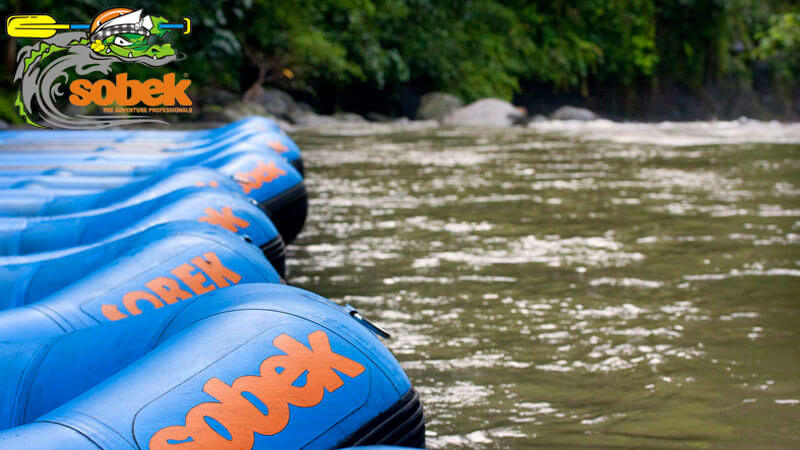 Perahu rafting Sobek siap di tepi sungai Bali, menunggu petualangan arung jeram berikutnya.