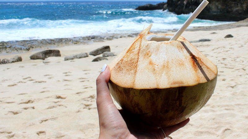 kelapa muda segar di tepi pasir putih dengan latar belakang ombak