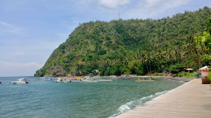 Pemandangan Pantai Labuhan Amuk dengan perahu-perahu dan latar bukit yang hijau