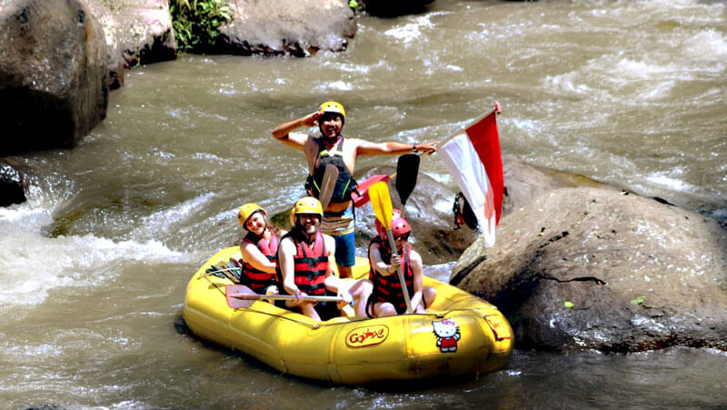 Peserta rafting mengibarkan bendera Indonesia saat menikmati arus Sungai Ayung dengan Payung Rafting Ubud