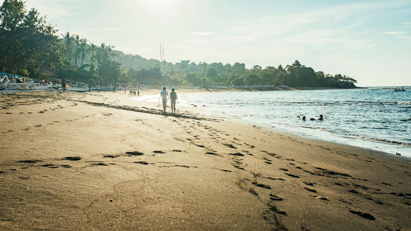 Pantai berpasir hitam di Bali Timur dengan pengunjung menikmati matahari terbit