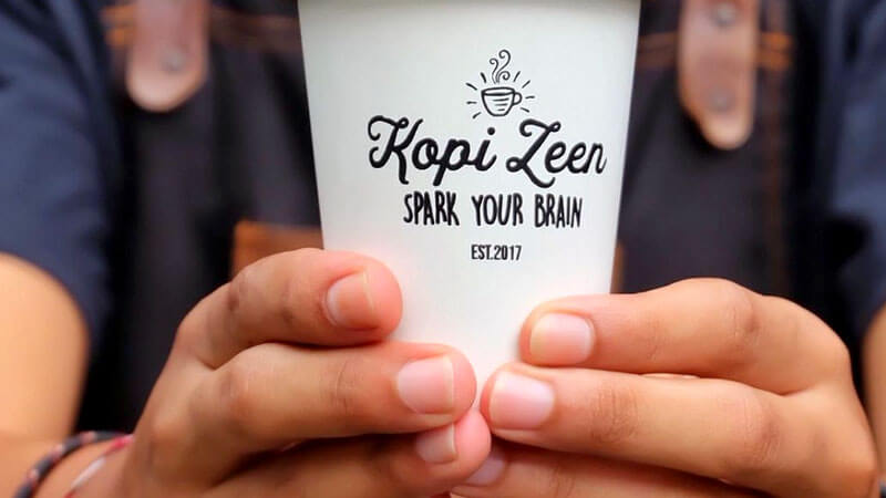 Cangkir Kopi Zeen yang ikonik dengan slogan 'Spark Your Brain' - spot hangout nongkrong asyik di Kuta.