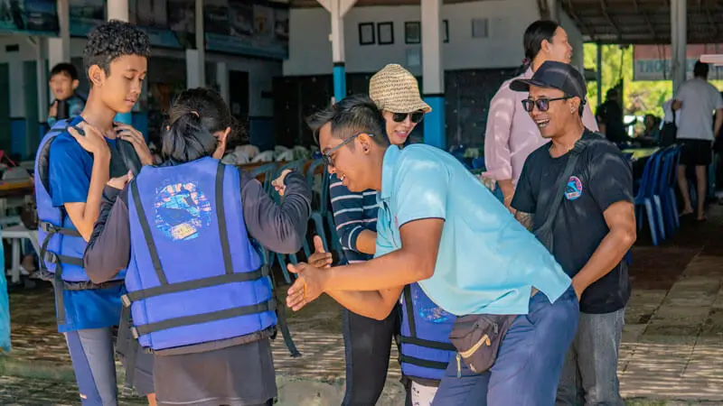 Instruktur membantu peserta memakai pelampung saat briefing keselamatan sebelum aktivitas watersport di Bali.