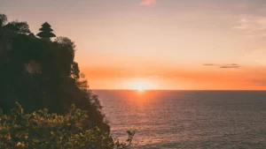Pemandangan indah dari Pura Luhur Uluwatu di Bali dengan latar belakang laut dan matahari terbenam yang spektakuler.