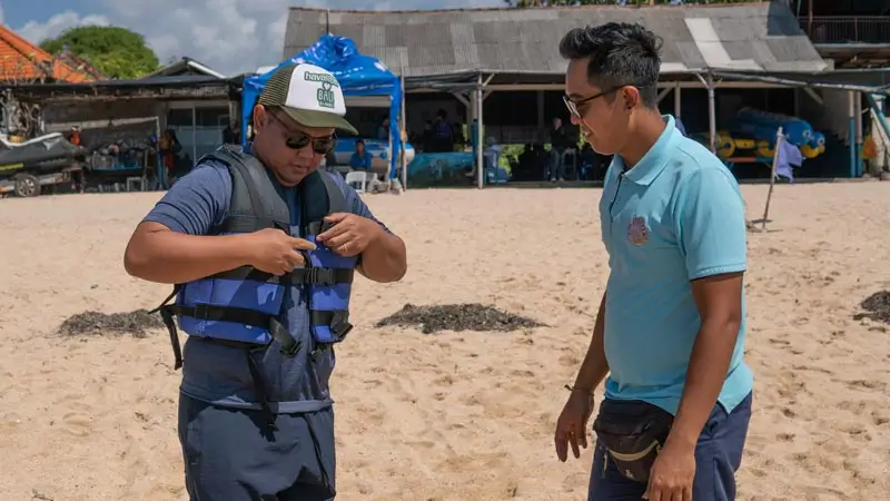 Staf membantu mengecek dan mengencangkan life jacket sebelum aktivitas water sport Bali