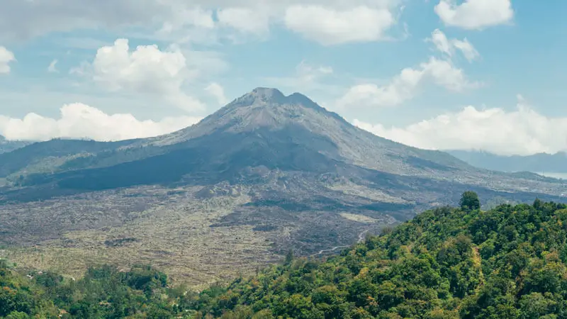 Gunung Batur di Kintamani Bali dengan lanskap hijau dan langit cerah.