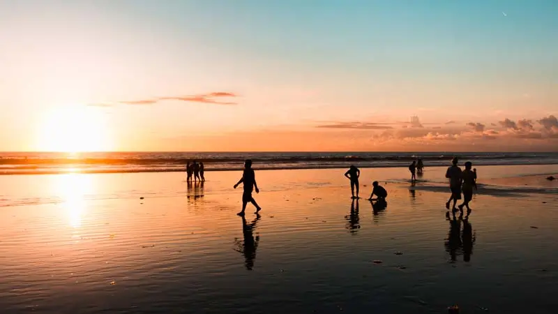 Sunset di Pantai Kuta Bali dengan siluet wisatawan menikmati suasana sore di tempat wisata Bali favorit.