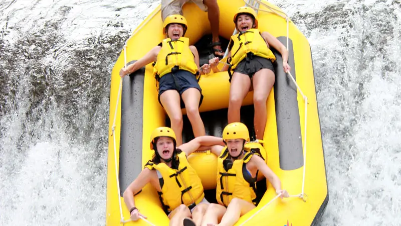 Peserta rafting di Sungai Telaga Waja, Bali, melewati turunan curam 5 meter dengan ekspresi penuh adrenalin dan kegembiraan.