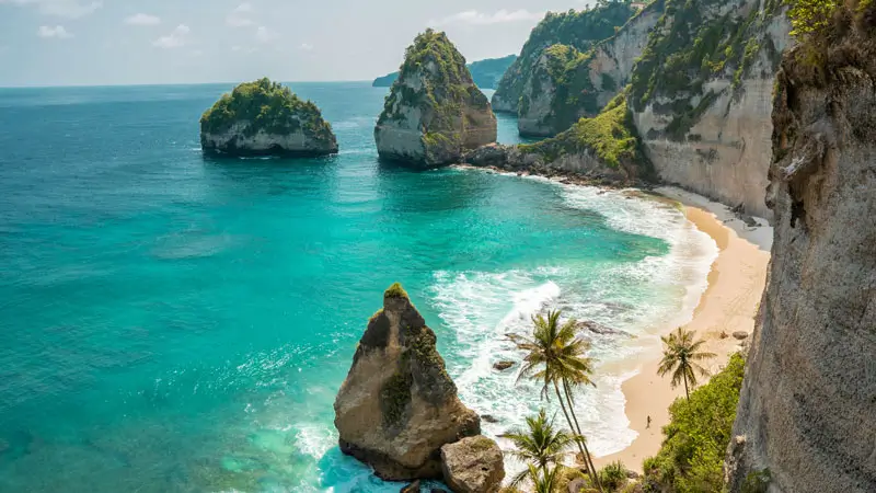 Pemandangan Diamond Beach Bali dengan tebing dan laut biru.