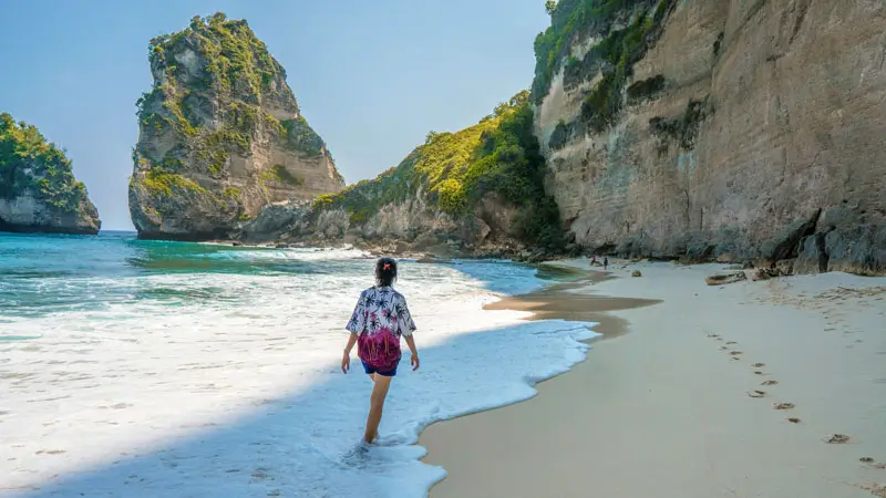 Wisatawan berjalan di bibir pantai Nusa Penida yang tenang.