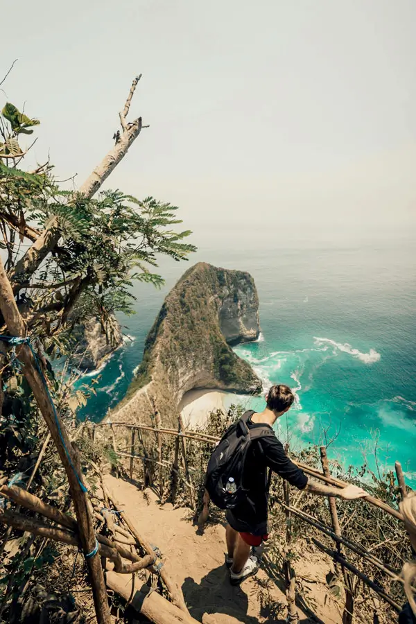 Jalur curam turun ke Pantai Kelingking dengan pagar bambu dan kayu.