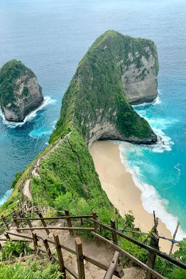 Spot foto premium di tebing Kelingking dengan latar laut biru.