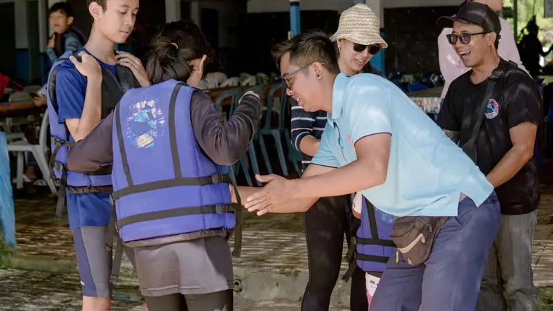 Prosedur keselamatan: staf bantu pasangkan pelampung ke peserta.