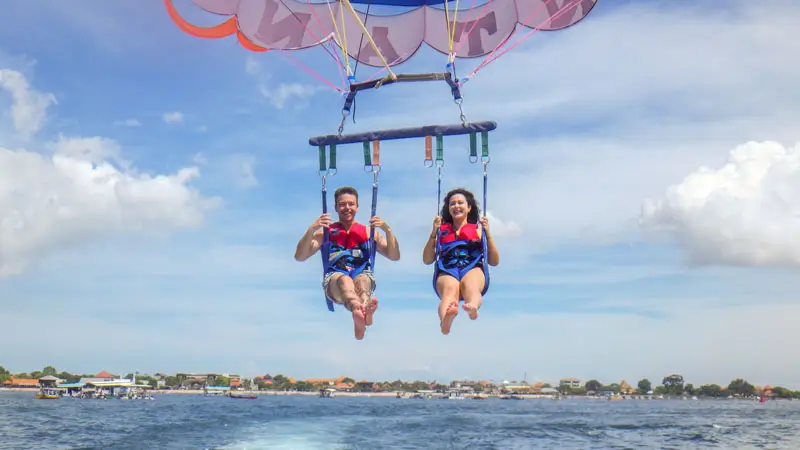 Dua pemula tersenyum saat parasailing di Tanjung Benoa Bali.
