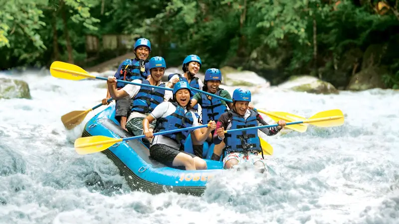 Grup peserta rafting tertawa bersama di atas perahu saat menyusuri arus Sungai Ayung