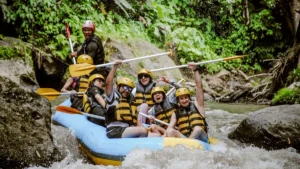 Peserta rafting mengangkat dayung dengan ekspresi senang saat menyusuri Sungai Ayung
