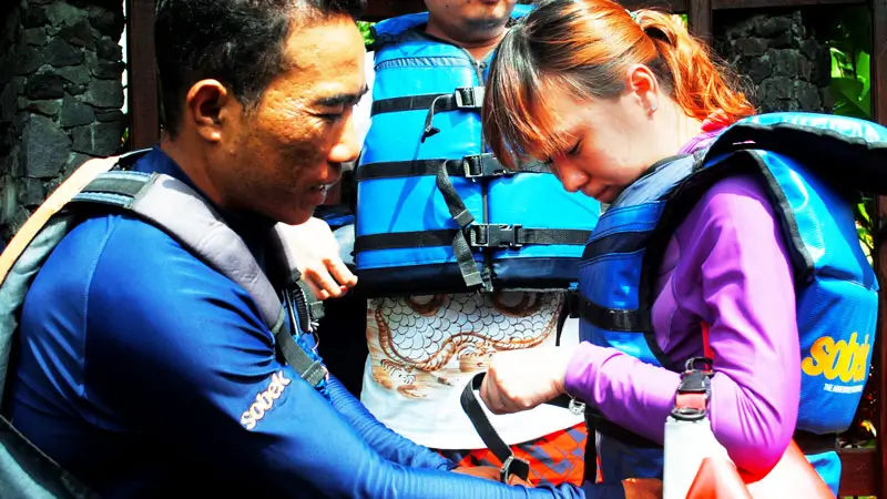 Pemandu memasang pelampung untuk peserta arung jeram