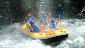 Peserta rafting Sobek Telaga Waja mengangkat dayung di bawah air terjun