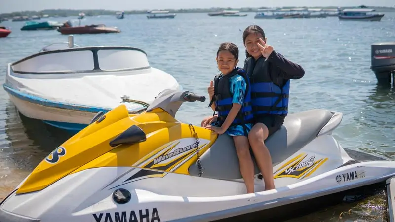 Anak duduk di jet ski untuk foto sebelum aktivitas