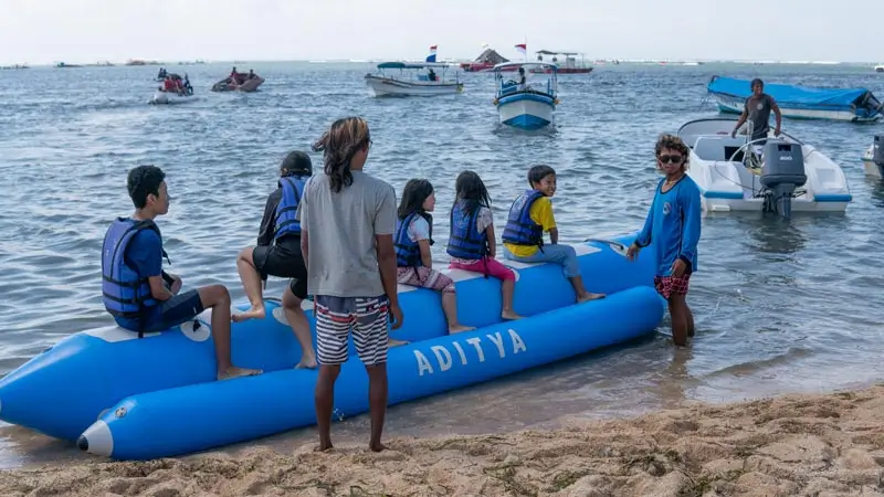 Keluarga duduk di banana boat sebelum ditarik di laut