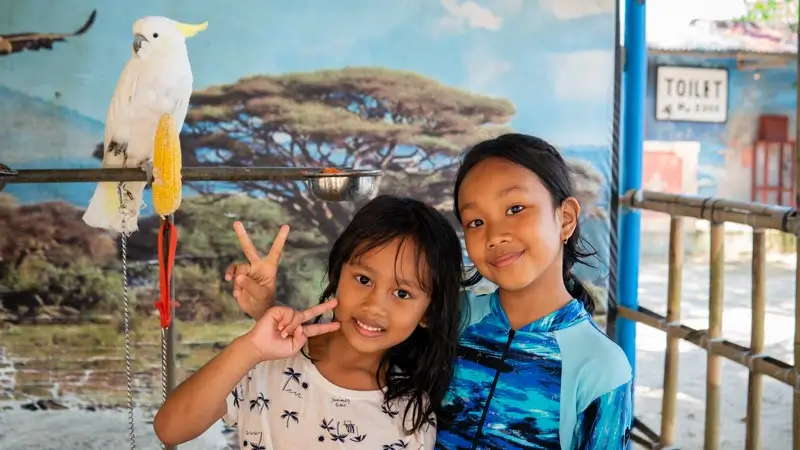 Anak berfoto dengan burung kakatua di area konservasi Pulau Penyu Tanjung Benoa