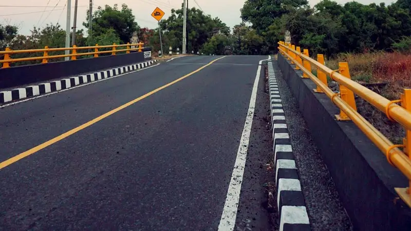 Jalan aspal di jembatan dengan pagar kuning, ilustrasi perjalanan darat di Tulamben Bali