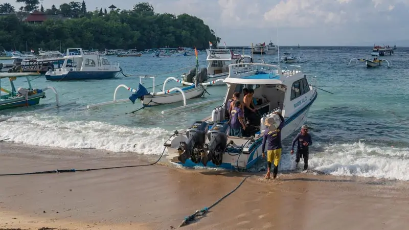 Tempat diving di Bali di Padang Bai: perahu sandar, kru membawa tabung selam