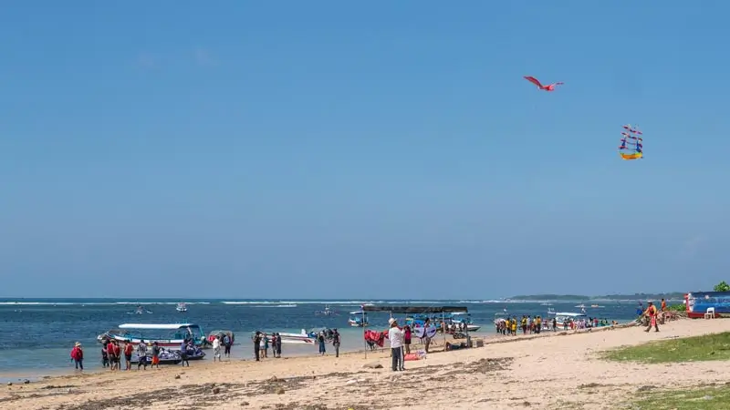 Suasana pantai Tanjung Benoa dengan boat dan wisatawan di latar