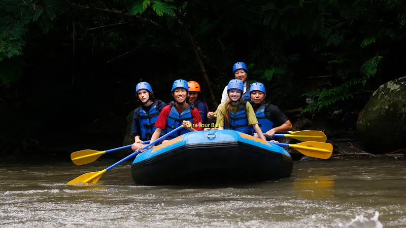 Grup arung jeram di Sungai Ayung Ubud melaju di arus tenang dengan latar hijau.
