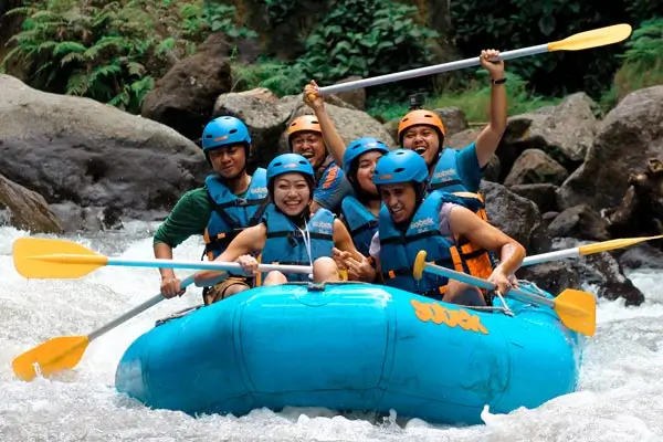 Peserta rafting di Sungai Ayung dengan helm dan pelampung di jeram berbatu.