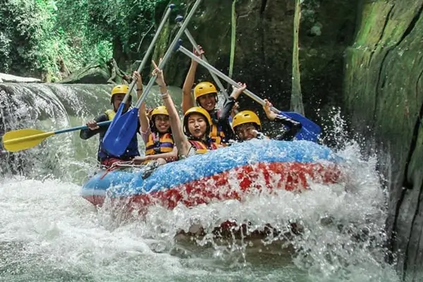 Perahu rafting di Sungai Melangit melewati jeram sempit dengan percikan air tinggi.