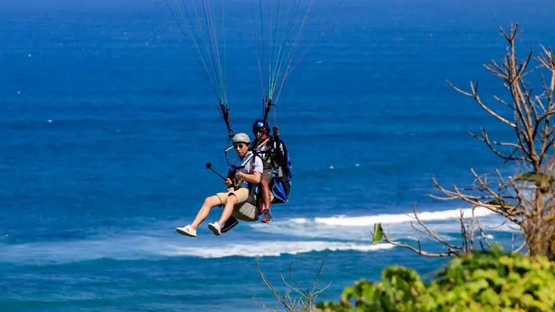 Tandem paragliding bersama pilot di atas laut