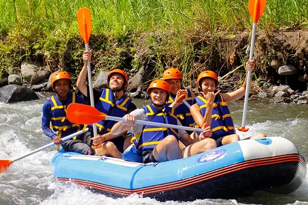Grup rafting di Sungai Telaga Waja mengangkat dayung di arus sungai yang deras.