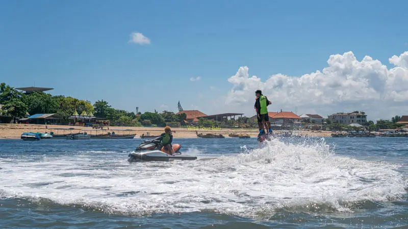 Peserta flyboard rendah di atas air dengan jetski pendamping