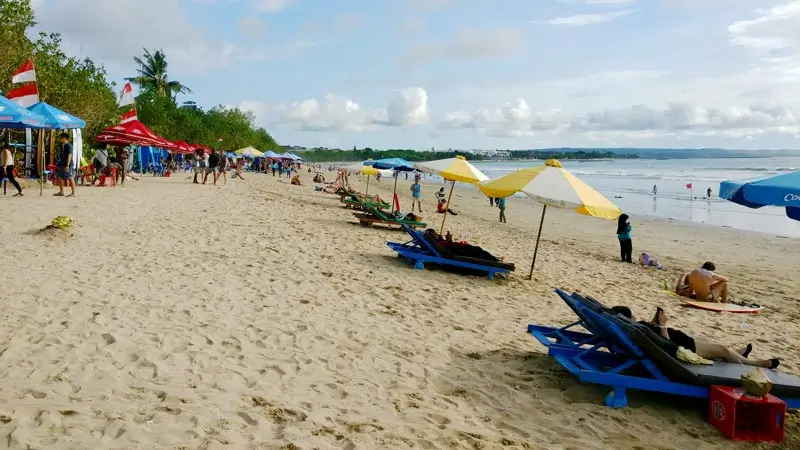 Kursi pantai, payung, dan suasana wisatawan di tepi pantai