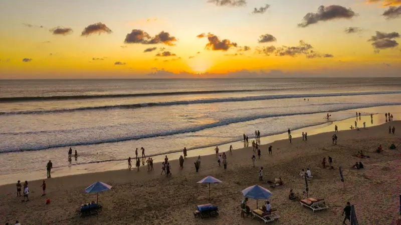 Wisatawan menikmati sunset di tepi pantai