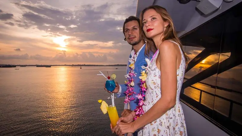 Tamu menikmati minuman di dek kapal saat sunset